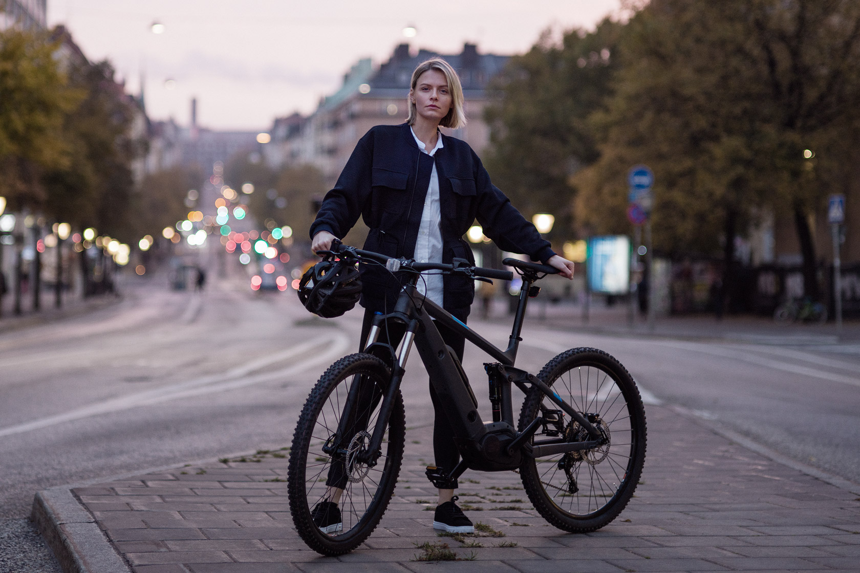 Young woman standing with her bicycle on a street in Stockholm